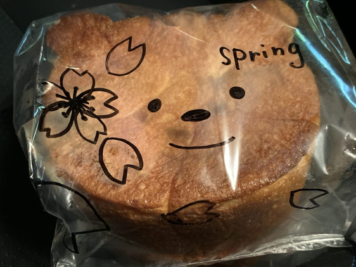クマの形のパンに包装の上からマジックでかわゆいクマちゃんと桜が描かれている